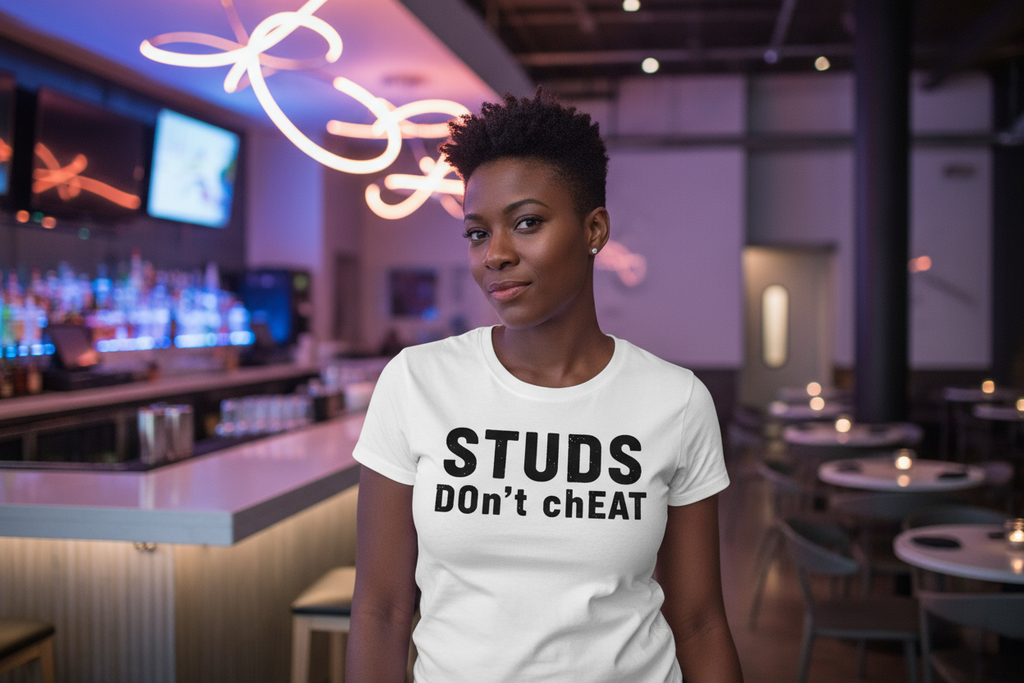 Person wearing a white t-shirt with 'STUDS DON'T CHEAT' text in a bar setting